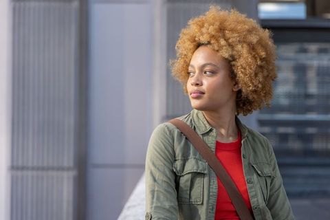 African american woman leaning on balcony railing looking thoughtful in urban portrait