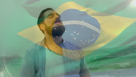 Dreamy Caucasian Man Overlaid with Brazilian Flag by Sea