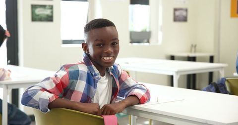African American Boy Smiling at School Desk with Pencil