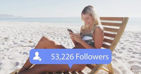 Influencer checking smartphone on sunny beach chair with 53,226 followers overlay