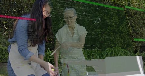 Woman painting in backyard with child helper, code overlay blending craft and coding