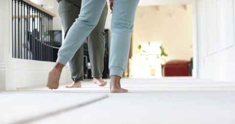 Barefoot african american women walking down bright carpeted hallway in sweatpants