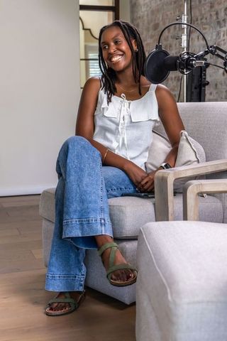 African american podcaster smiling while recording in cozy home studio lounge