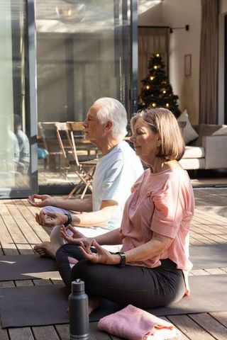 Senior Couple Meditating Outdoors with Fitness Trackers in Tranquil Yard