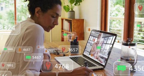 Remote coworker writing at home workspace with laptop video call and notification overlays