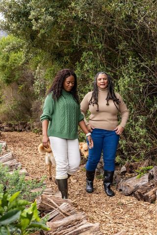 African american senior and adult women walking woodchip trail with golden retriever in nature