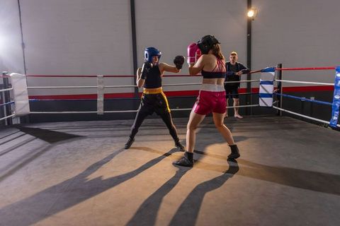 Male and female boxers sparring in ring under dramatic gym lighting