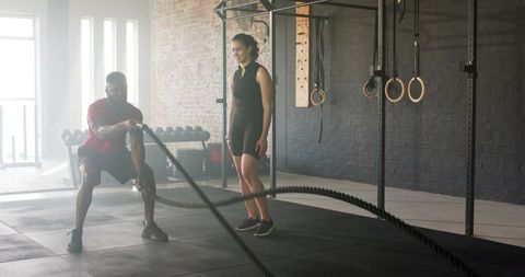 Trainer instructing battle ropes workout for improved strength