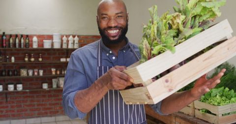 Smiling grocer holding fresh vegetables at organic market stand