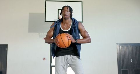 Focused Basketball Player Holding Ball in Gym Environment