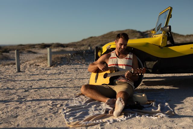 Caucasian Man Playing Guitar on Beach by Beach Buggy at Sundown - Download Free Stock Photos Pikwizard.com