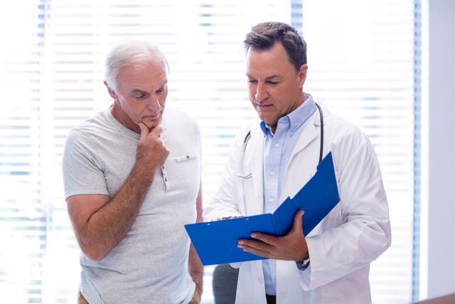Doctor discussing medical report with senior patient in clinic. Ideal for use in healthcare, medical consultation, elderly care, and patient-doctor interaction contexts. Useful for illustrating medical advice, diagnosis, and professional healthcare services.