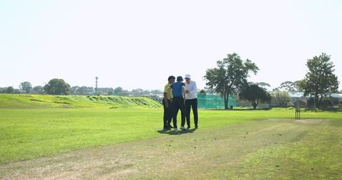 Cricket Teammates Strategizing on Pitch in Outdoor Training