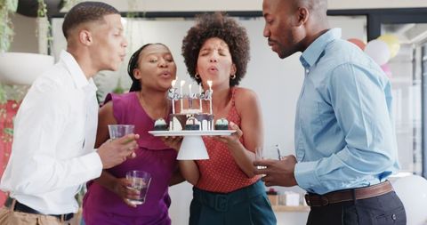 Diverse colleagues celebrating birthday at office party