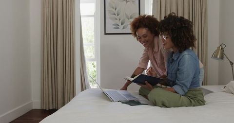 African American Women Collaborating and Planning on Laptop in Modern Bedroom