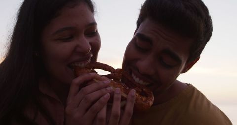 Joyful Couple Sharing a Pretzel at Sunset - Download Free Stock Images Pikwizard.com