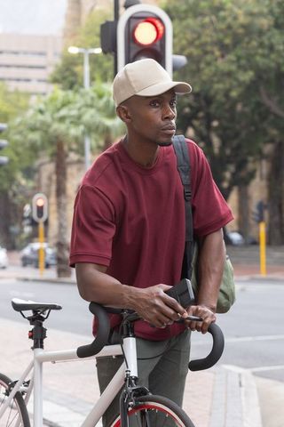 African american commuter standing by road bike at urban intersection checking smartphone
