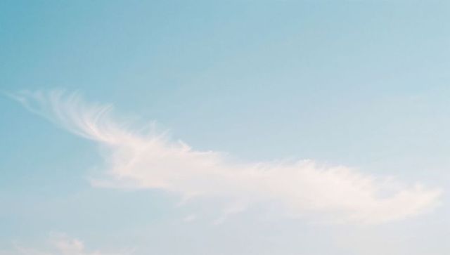 Feathery cirrus cloud stretching across soft blue sky, minimalist serene daylight