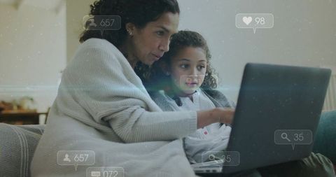 Mother and daughter watching laptop together while viewing social media notifications at home