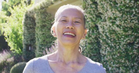 Joyful Senior Woman Smiling Outdoors in Lush Garden