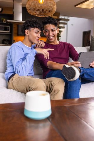 Friends Using Tablet on Sofa with Smart Speaker Nearby
