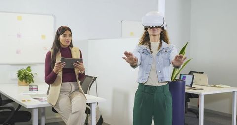 Diverse female coworkers conducting virtual reality usability testing in modern office