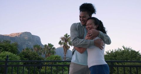 Couple Embracing Outdoors with Mountains and Palm Trees