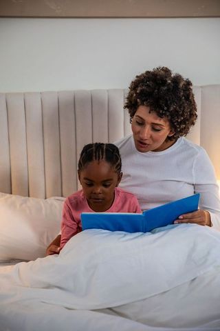 Mother and Daughter Reading Storybook at Bedtime