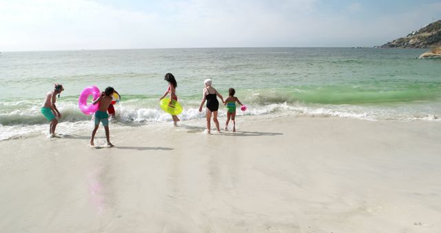 Family with water tubes enjoying summer day at sandy beach. Ideal for themes like family vacations, leisure, beach activities, summer fun, or travel. Perfect for promoting travel destinations, vacation packages, and outdoor activities.