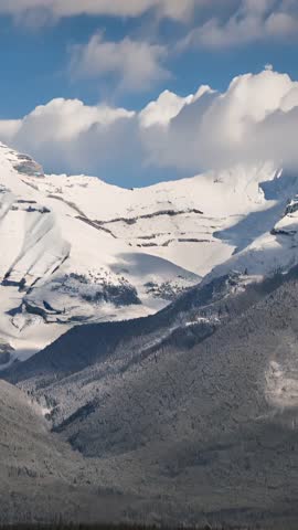 Vertical Video Clouds Drifting over Snowy Alpine Peaks and Forested Mountain Valley