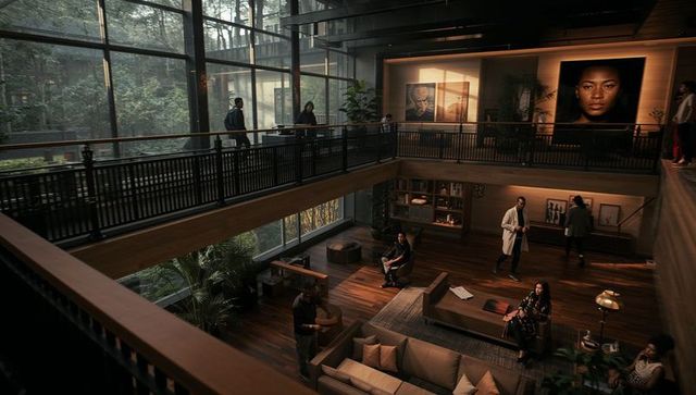 Professionals networking in modern glass atrium lounge with mezzanine and portraits