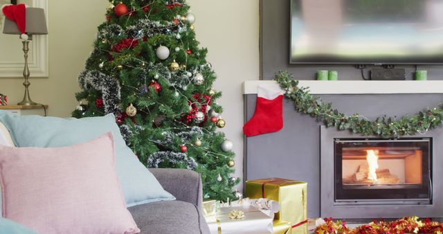 Perfect for showcasing festive holiday home decor ideas, this image features a cozy living room adorned with Christmas decorations. There is a beautifully decorated Christmas tree beside a burning fireplace, which is garnished with a hanging stocking and green garland. Presents are placed underneath the tree, adding to the festive atmosphere.