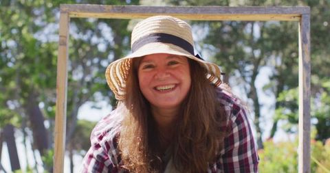 Smiling Woman Gardening in Sunlight Wearing Straw Hat