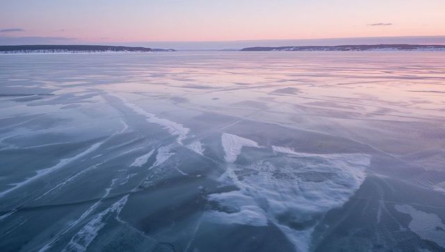 Serene frozen lake during dawn with snowy shores