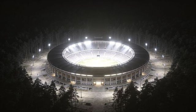 Glowing circular stadium surrounded by forest with floodlights at night