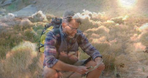 Rugged Hiker Studying Map With Tablet in Sunny Meadow Outdoors