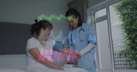 Asian senior woman with nurse monitoring blood pressure at home
