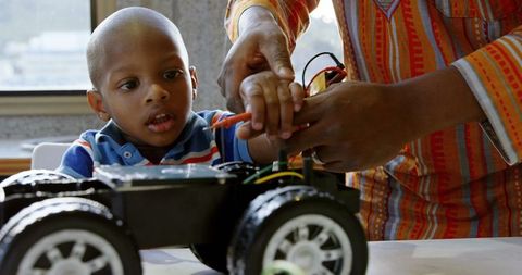 Father Teaching Son to Repair Remote-Control Car at Home