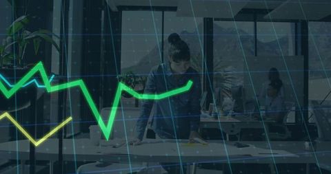 Focused businesswoman analyzing data in open-plan office with digital financial charts