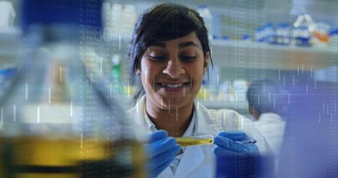 Smiling female scientist examining yellow reagent in test tube with digital data overlay
