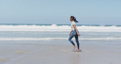 Woman Enjoying Beach Walk Under Blue Sky