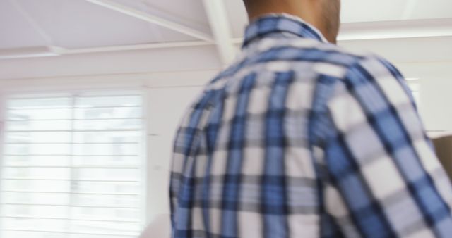 Man with Plaid Shirt Walking Inside Bright Room - Download Free Stock Images Pikwizard.com