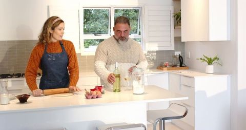 Couple Baking Together in Bright Modern Kitchen Pouring Wine and Rolling Dough at Island