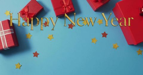 Gold happy new year lettering with red gift boxes and glitter stars on cyan background flatlay holid