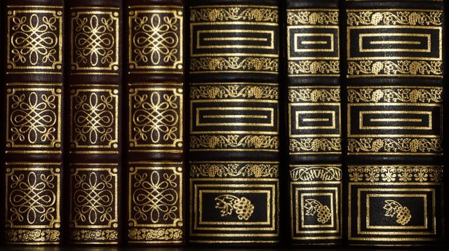 Classic vintage leather-bound books with intricate golden detailing on their spines. Perfect for themes such as historic libraries, antique collections, creative writing inspirations, classic literature studies, and elegant home decor materials.