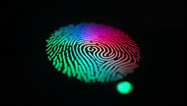 Glowing neon fingerprint scanner showing multicolor biometric touch id closeup for security