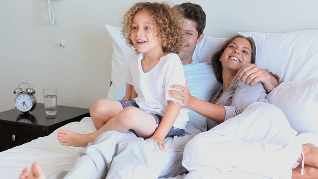 Family enjoys relaxed morning, child joyfully bounds into view creating moment of laughter. Perfect for lifestyle family products, promoting happiness at home, ideal for family-centered marketing campaigns.