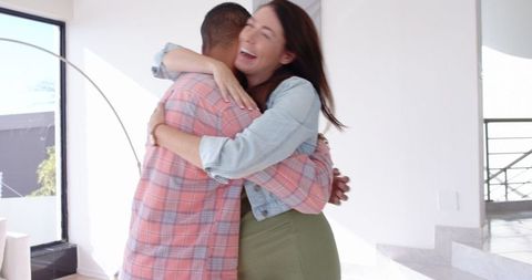 Female Friends Embracing Joyfully in Sunny Living Room