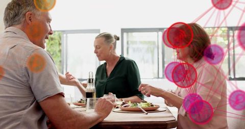Mature adults sharing healthy lunch around wooden table with digital network overlay