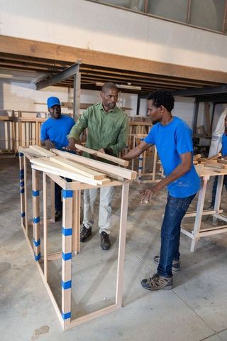 African american team assembling wooden frames, collaborating on carpentry training
